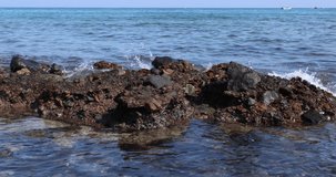 Video of a rocky shoreline against the rocks of which crash waves of the Gulf, where you can see the beautiful blue water and reefs.