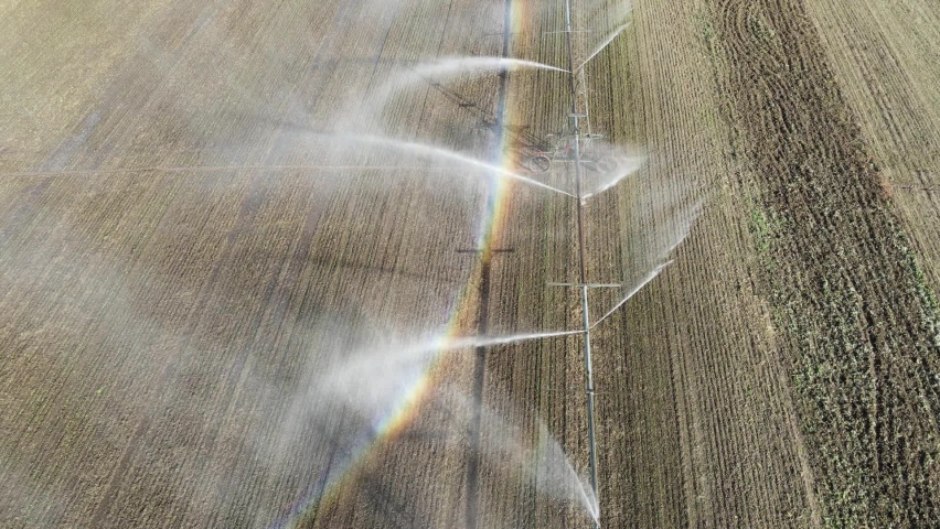 View of water sprinkling in the field. Pivot irrigation used to water plants on a farm. Smooth movement, circular pivot irrigation with drone - agriculture 