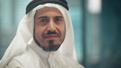 Portrait of Successful Arab Businessman in Traditional Outfit Gently Smiling, Wearing White Kandura and Black Agal Keeping a Ghutra in Place. Saudi, Emirati, Arab Businessman Concept.