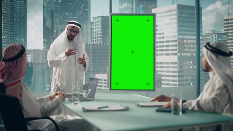 Emirati Businessman Holds Meeting Presentation for Business Partners. Arab Manager Uses Digital Whiteboard with Vertical Green Screen Mock Up Display. Saudi, Emirati, Arab Office Concept.