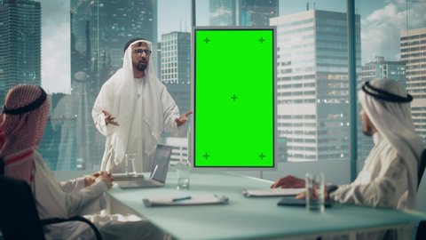 Emirati Businessman Holds Meeting Presentation for Business Partners. Arab Manager Uses Digital Whiteboard with Vertical Green Screen Mock Up Display. Saudi, Emirati, Arab Office Concept.