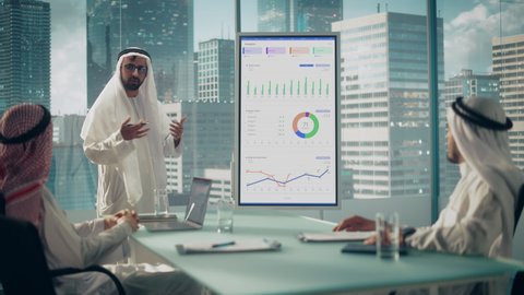 Emirati Businessman Holds Meeting Presentation for a Business Partners. Arab Manager Uses Digital Whiteboard with Growth Analysis, Charts, Statistics and Data. Saudi, Emirati, Arab Office Concept.