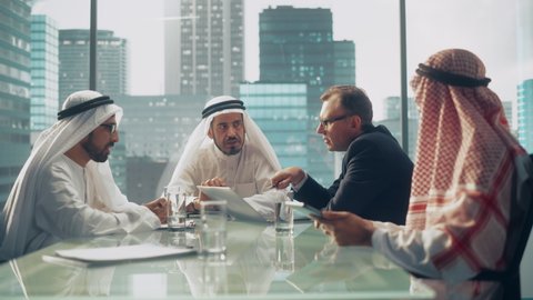 International Business Consultant Advices on Diversification of Investment Portfolio to Successful Arab Company Owners. Multicultural Meeting in Modern Office Between European and Emirati Businessman