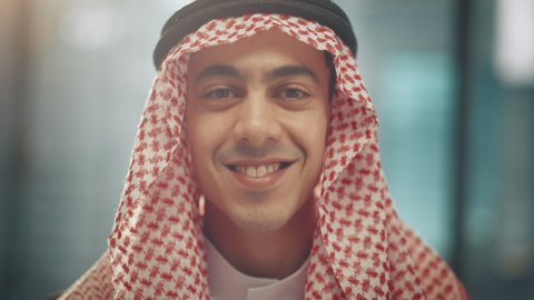 Portrait of Young Successful Arab Businessman in Traditional Outfit Gently Smiling, Wearing White Kandura and Black Agal Keeping a Ghutra in Place. Saudi, Emirati, Arab Businessman Concept.