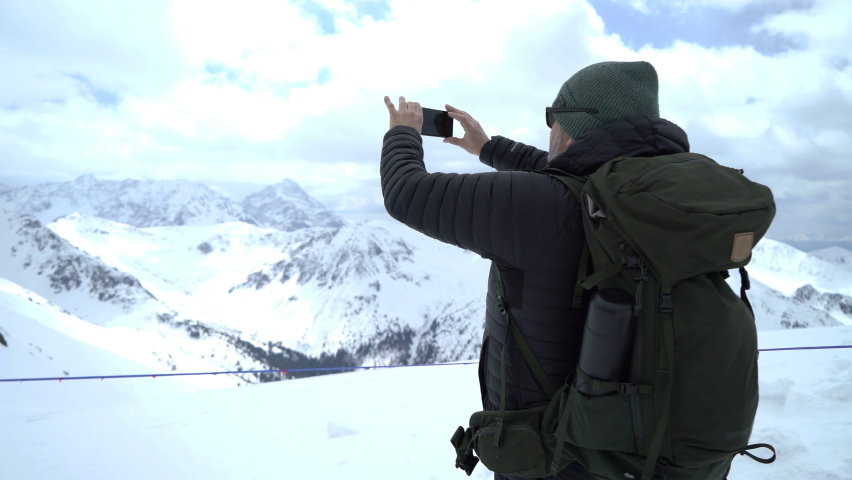 Man uses a smartphone to video a beautiful view in the mountains
