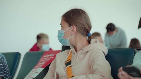 Portrait of a teenage girl in a medical mask sitting at the airport.