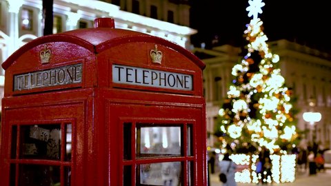 Christmas in London: a classic, red telephone booth in front of an illuminated Christmas Tree in Central London, United Kingdom