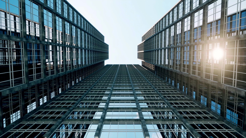 Sunlight reflecting off glass skyscrapers as the camera moves from ground level up to the clear blue sky above.
