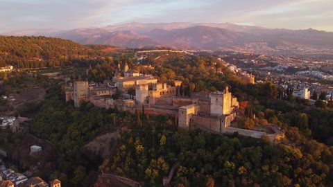Dramatic aerial drone footage of the famous Alhambra palace and fortress in Granada, Andalusia, in Spain at sunset. Shot with a rotation motion. 