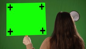 Looking away, a woman holds a green screen chroma key blank sign and points to the sign on green screen background. - Powered by Shutterstock - Get 15% off with code: PIKWIZARD15