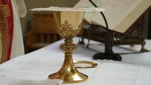 The priest says a prayer over the golden chalice intended for the holy communion after confession.