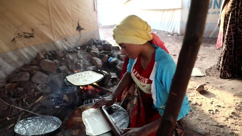  ( medium shot ) A  woman cooks inside a tent at a temporary camp for people displaced by the conflict in Taiz , Yemen , Taiz on  20 November 2021