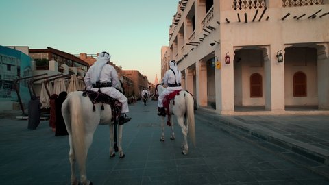 Doha, Qatar- November 23 2021: Souq Waqif Doha, Qatar main street afternoon shot showing traditional policemen riding horses , Locals and visitors walking