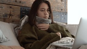 sick young female patient in sweater talk to doctor , medical consultation on videocall on laptop in telehealth, telemedicine. attractive woman coughing, sneezing. coronavirus, flu, 4k footage