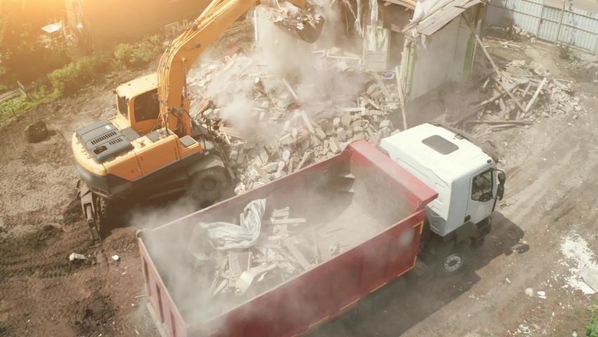Demolition of building. Excavator loads construction waste into truck for removal from construction site, aerial view Royalty-Free Stock Footage #1082811601