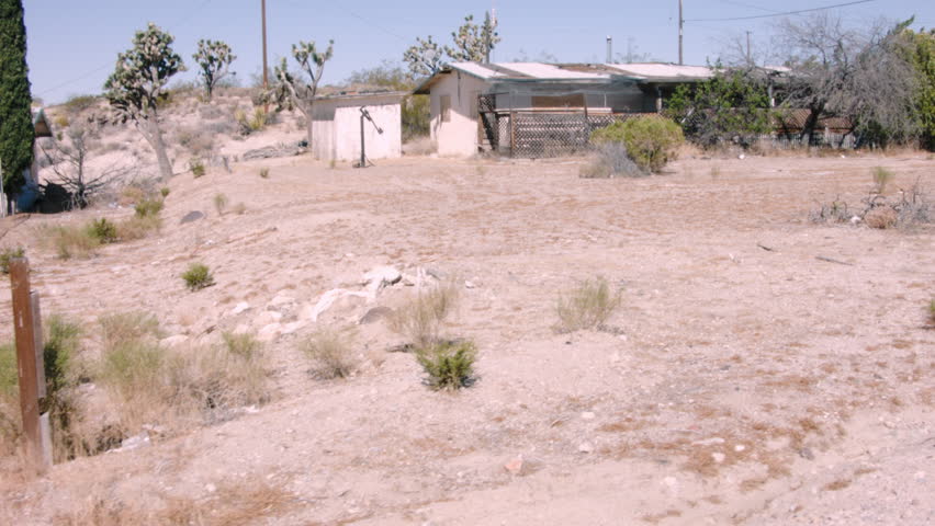 ABANDONED MOBILE HOME ESTABLISHING SHOT. 2 OF 2.  TRACKING SHOT ALONG THE FRONT OF A WINDOWLESS, GRAFFITI COVERED MOBILE HOME SITTING IDLE IN THE CALIFORNIA DESERT.