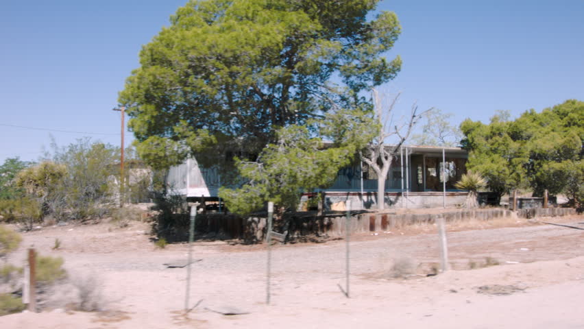 ABANDONED MOBILE HOME ESTABLISHING SHOT. 2 OF 2.  TRACKING SHOT ALONG THE FRONT OF A WINDOWLESS, GRAFFITI COVERED MOBILE HOME SITTING IDLE IN THE CALIFORNIA DESERT.