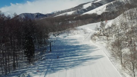 Snowboarder glides down an empty ski field Hakuba Japan.