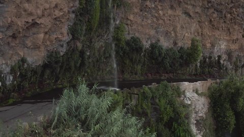 Aerial shows a VW-Camper van driving through a waterfall, Cascada dos Anjos, Ponta do Sol, Madeira