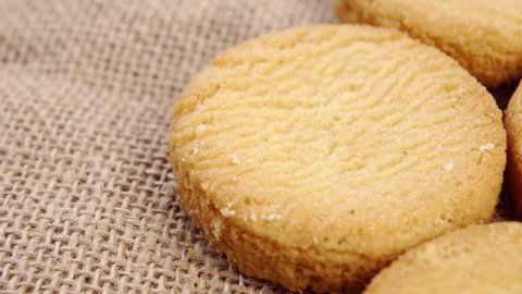 Shortbread biscuits on a rustic rough burlap. Macro. Slow rotation. Fresh homemade cookies