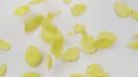 Cornflakes Falling On White Surface, Close-up. Falling Corn Flakes. Ready Healthy Cornflakes Breakfast. Cornflakes background. Healthy Vegetarian Food.