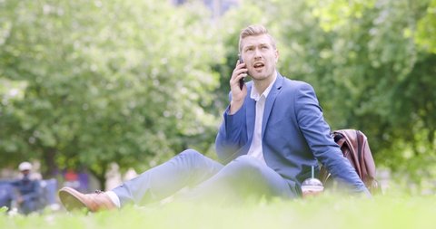 Businessman talking on the phone sitting on grass