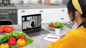 Man food blogger in computer screen shows slice cucumber tells teaches housewife online video call laptop. Woman in home kitchen study remote culinary lesson listen chef teacher, drinking coffee tea