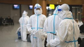 Chinese passengers, tourists or travelers at airport terminal changing in Covid-19 uniforms. Facemasks and face shields, airplane coronavirus. Medics in covid 19 suits clothing before plane boarding. - Powered by Shutterstock - Get 15% off with code: PIKWIZARD15