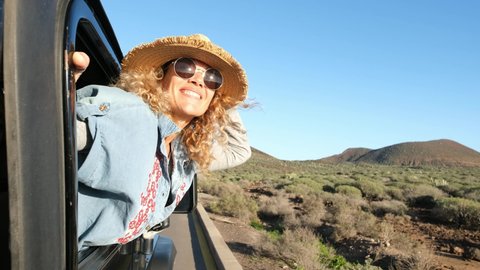 Happy woman looking out of car window on a road trip