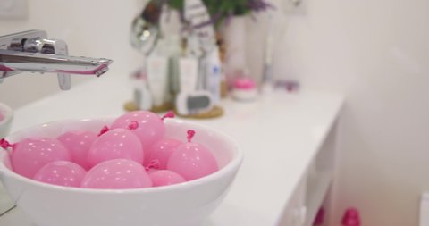 a bunch of pink water balloons in a sink. ready to kid's water fight. leisure activity
