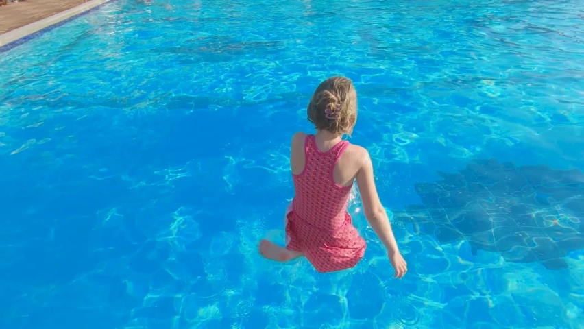 Child girl jump in swimming pool. Vacation or holiday. Huge water splash | Shutterstock HD Video #1082844676
