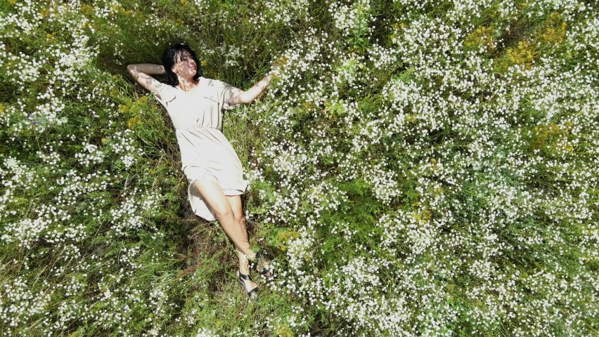 Drone aerial view of relax woman in dress lying on flower blooming meadow, in countryside, in the field on summer day, feel the nature, alone travel. Slow motion, top view. Royalty-Free Stock Footage #1082845195
