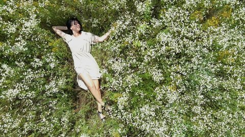 Drone aerial view of relax woman in dress lying on flower blooming meadow, in countryside, in the field on summer day, feel the nature, alone travel. Slow motion, top view. Stock Video