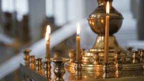 Candles are burning on a candlestick in a church, close-up, several wax candles, church, day, 4K video