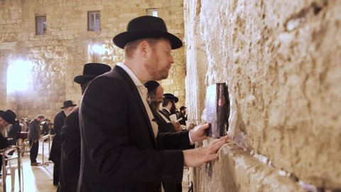 Jerusalem, Israel – Nov 22, 2021:  Jew praying at the Kotel very emotional. Orthodox Jew in front of the Wailing Wall reading a Sidur book and praying hard to god. Religious Jews praying in Jerusalem