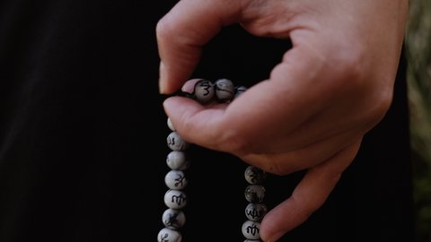 Woman is praying, repeating, chanting a mantra with a japa mala. Concept for religious practice in Hinduism, Jainism, Buddhism, Sikhism, Islam, and Christianity.