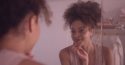 Young adult female smiling at her reflection in mirror