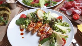 Stock food video of chicken Caesar salad with croutons, parmesan cheese and microgreens served on white plate in Mediterranean restaurant and filmed in 4k ultra hd