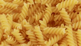 fusilli pasta in a white plate. pasta falling fall from the top. italian cuisine, eating carbs. whole grain fusilli.meniu,diet, weight loss nutrition close up video.