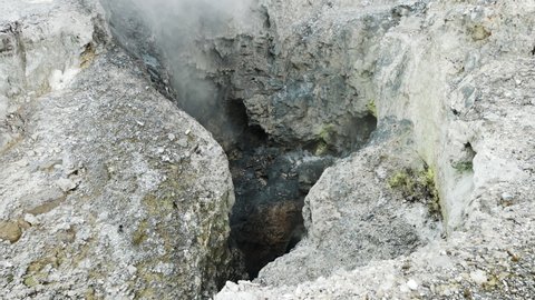Tilt up shot of fumes rising up between rocks at Wai-o-Tapu National Park - Boiling water pools between rock formation