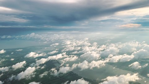 Aerial view from airplane. Flying above clouds, forest, lake and mountain. Aerial footage.