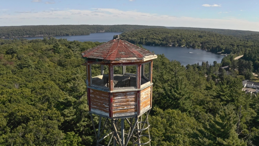 Rotating shot around fire lookout tower beside lake in rural Ontario cottage country