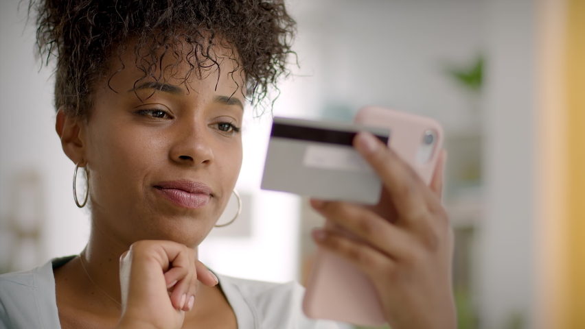 
Happy and Smiling African American Woman Making a Card Payment Through Mobile Phone  Attractive Black Girl Putting Debit or Credit Card Details on a Smartphone. Online Shopping.  | Shutterstock HD Video #1082868166