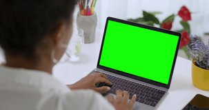 
Over the Shoulder Shot of African American Business Woman Typing on Laptop, Young Female Professional Writing an Important Email From Her Home in Modern Living Room. Remote Working. Green Screen.