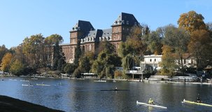 Many canoes moving over river Po with Valentino Castle at background in fall season. Turin, Piedmont, Italy, 