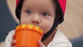 Face of happy toddler in baby safety helmet, cute kid smiling playing in infants playpen. Safe activity center keeping child away from hurt. High quality 4k footage