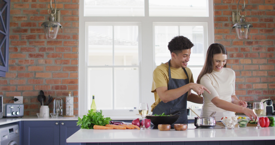 Happy biracial couple cooking together and laughing in kitchen. quality time, relaxing together at home. | Shutterstock HD Video #1082877439