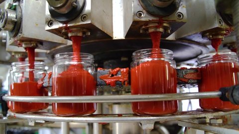 Automatic Line for Processing of Vegetables. Glass jars with vegetables pasta on conveyor belt. Bottling Tomato Paste in Glass jars. Adlı Stok Video