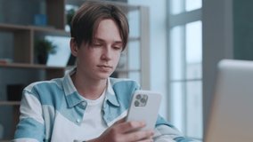 Handsome Teen Using Smartphone in Home Room at Side View. Attractive Young Man Communication Chatting on Social Networks Online. Student Listening Music on Cellphone. Concept People Leisure App Browse
