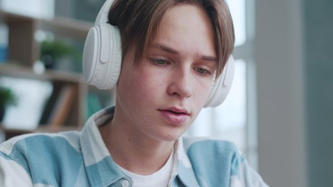 Handsome Teenager Man in Headphones Listening to Music at Home Close up. Attractive Smart Teen Guy Relaxing at Song Sound on Audio Device. Young Man Student Sing Leisure Recreation at Favorite Music